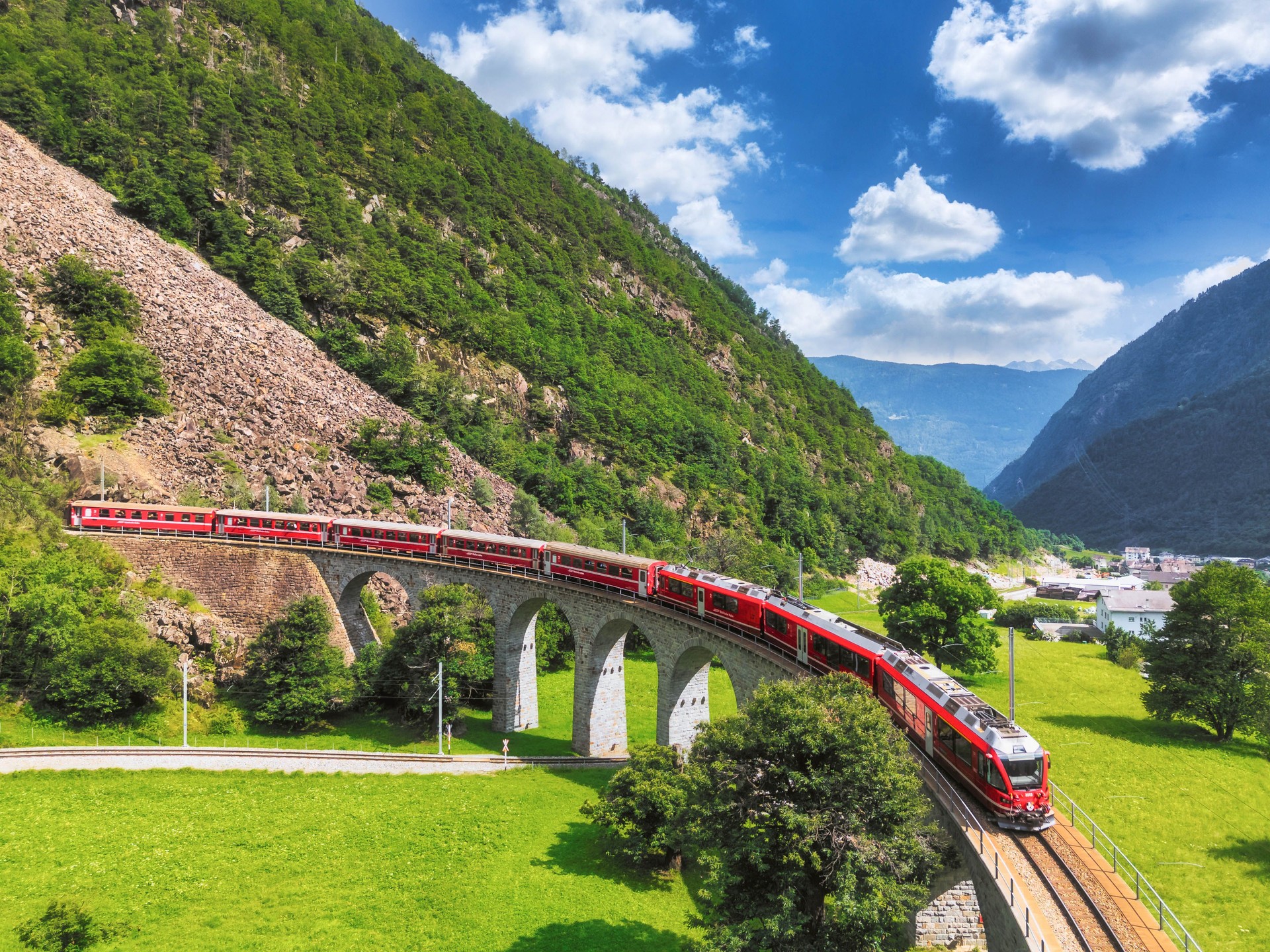 Aerial view of a Bernina Express train crossing the Brusio spiral viaduct of Rhaetian Railway, Grisons canton, Switzerland